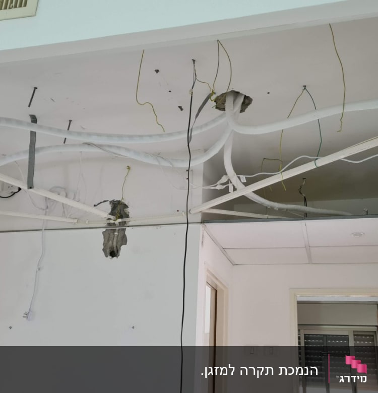 תקרת גבס פתוחה עם חוטי חשמל וצינורות חשופים